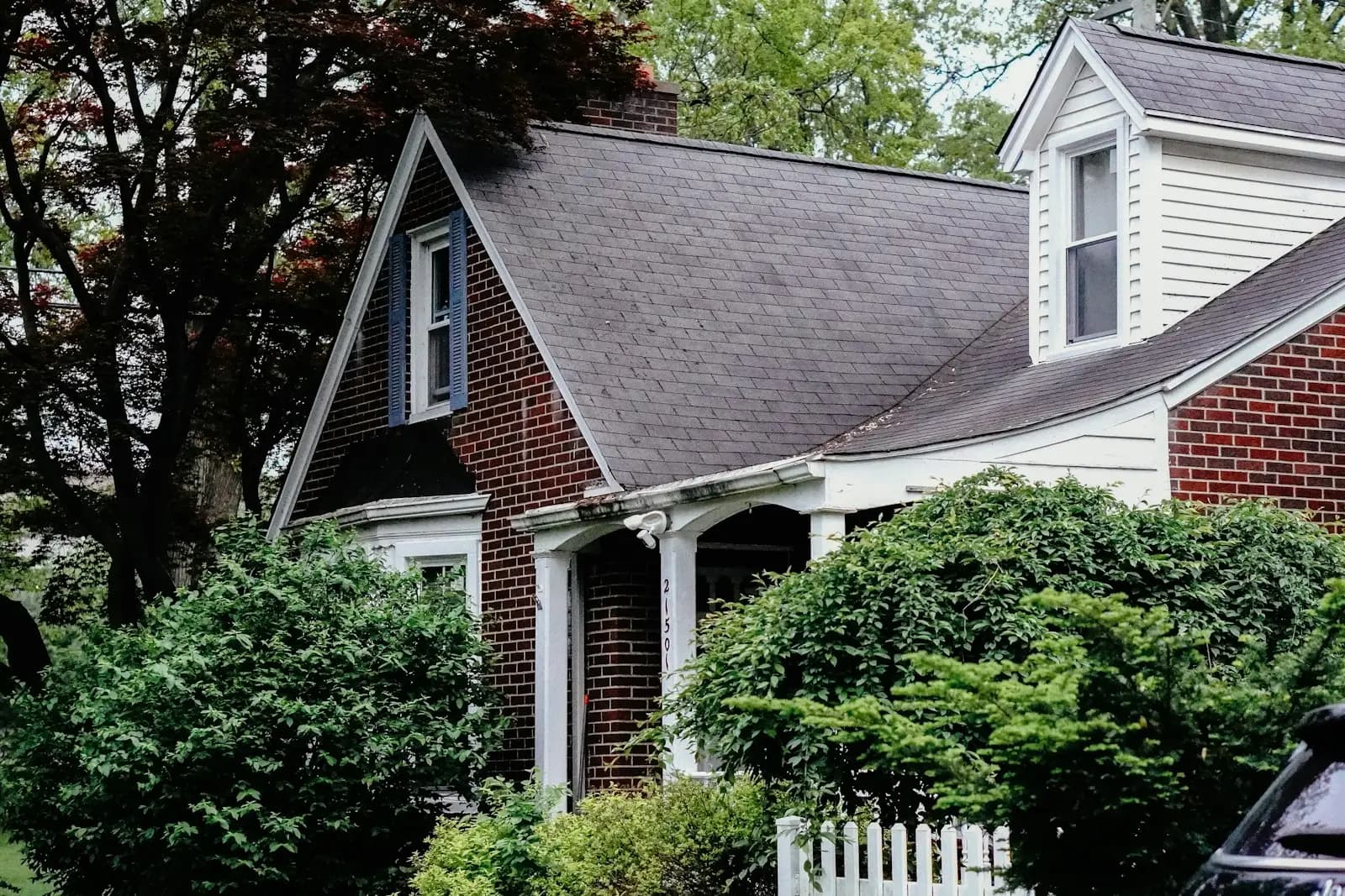 Brick Cape Cod home with a freshly replaced shingle roof