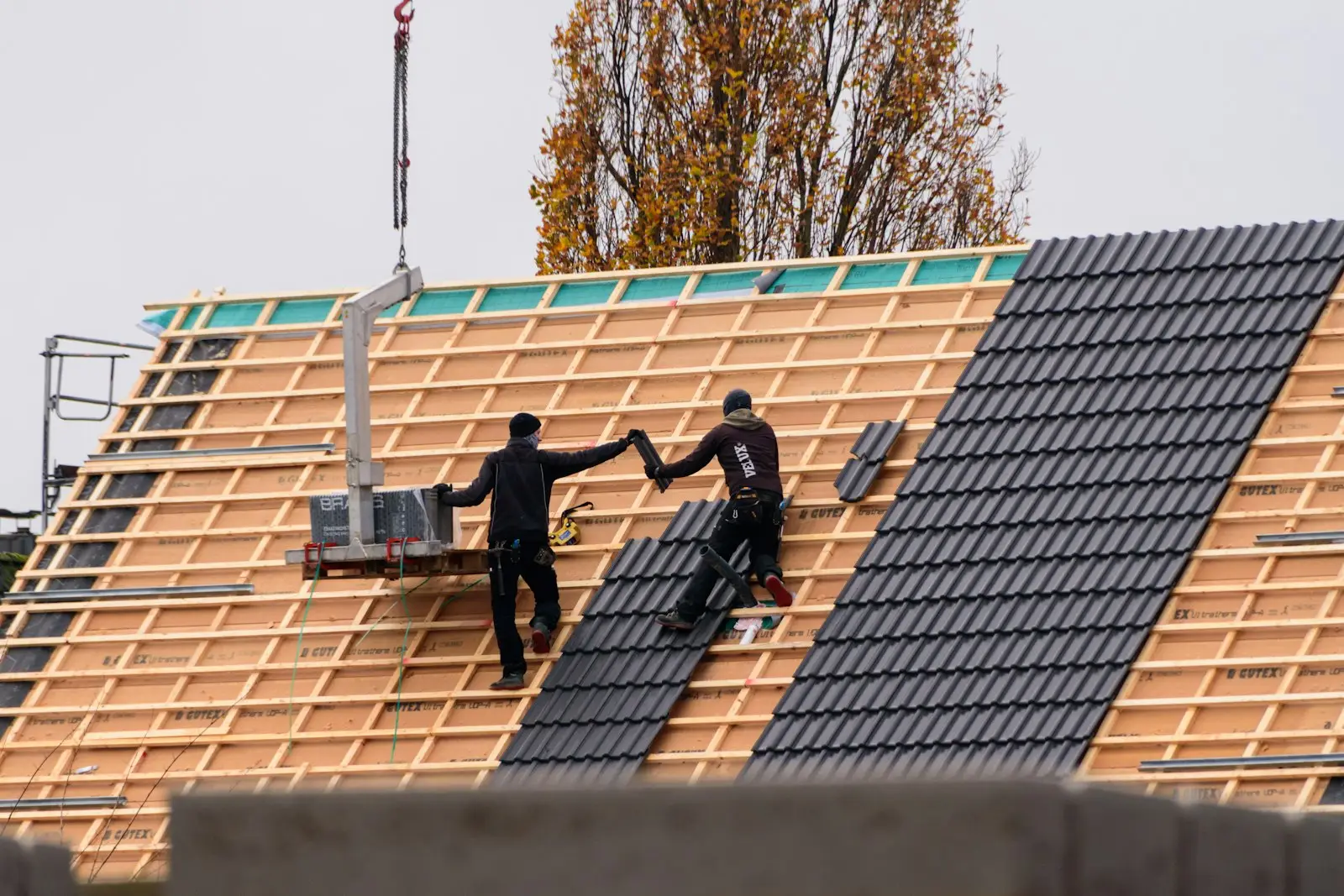 Crew installing roof panels on a new commercial building with a lift