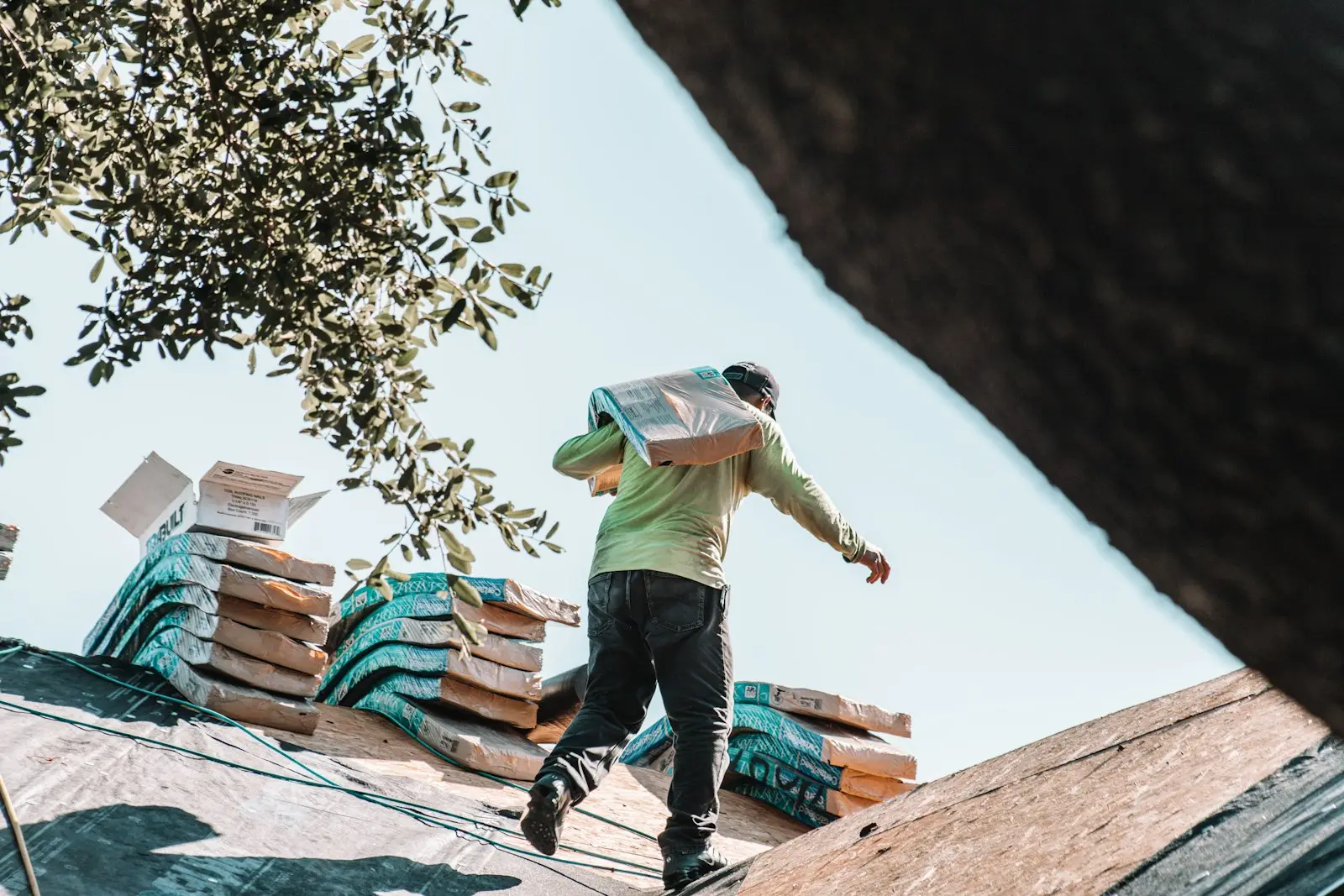 Roofer carrying shingle bundles across the Delaware farmhouse roof