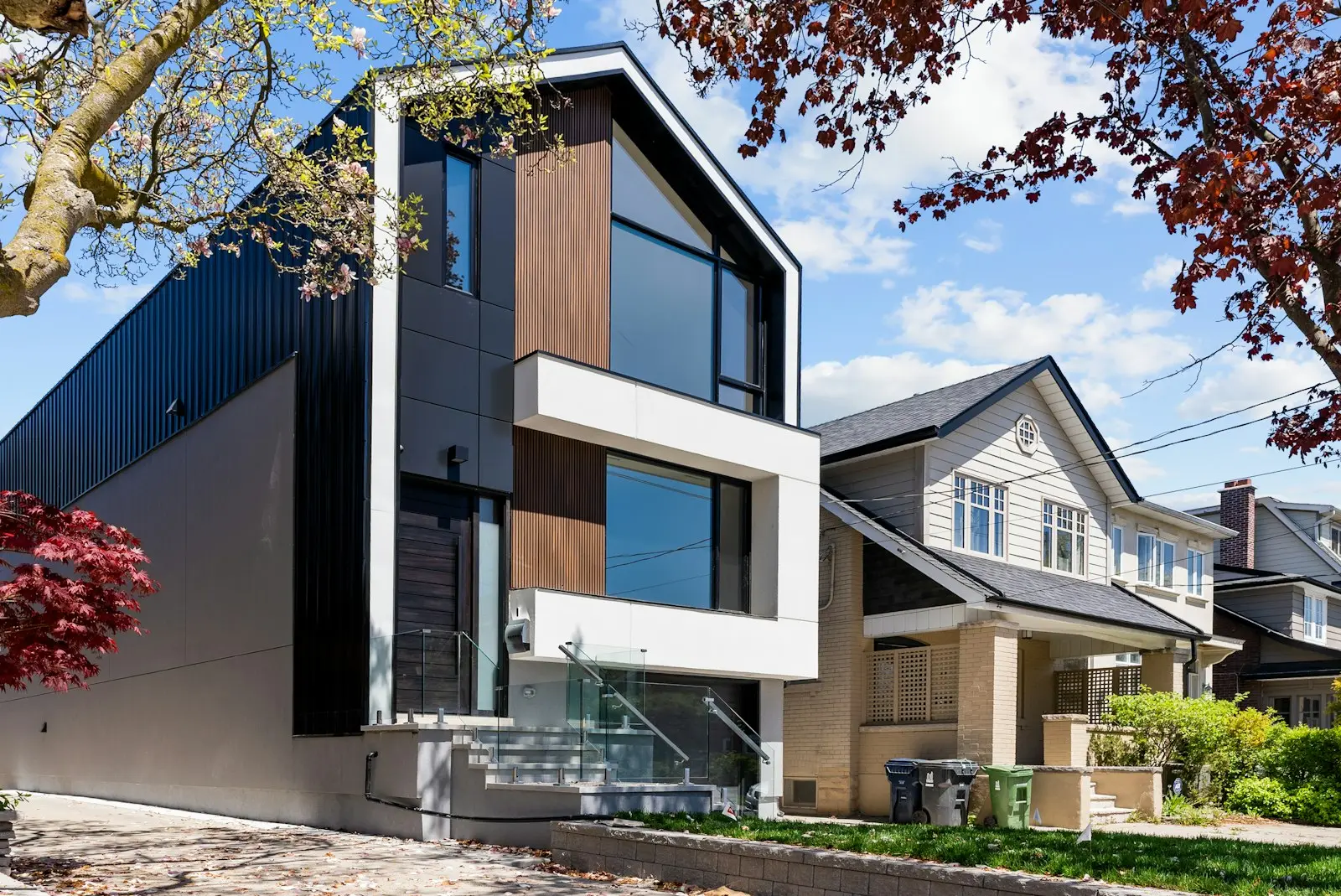 Contemporary black metal clad house next to a traditional home