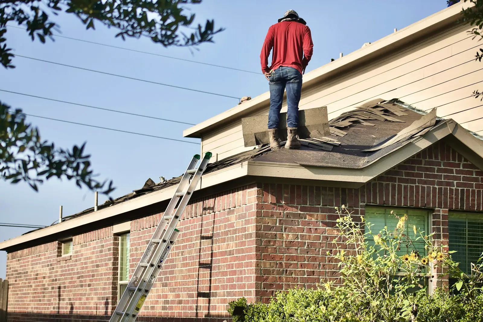 A Hartline inspector standing on a brick home's roof